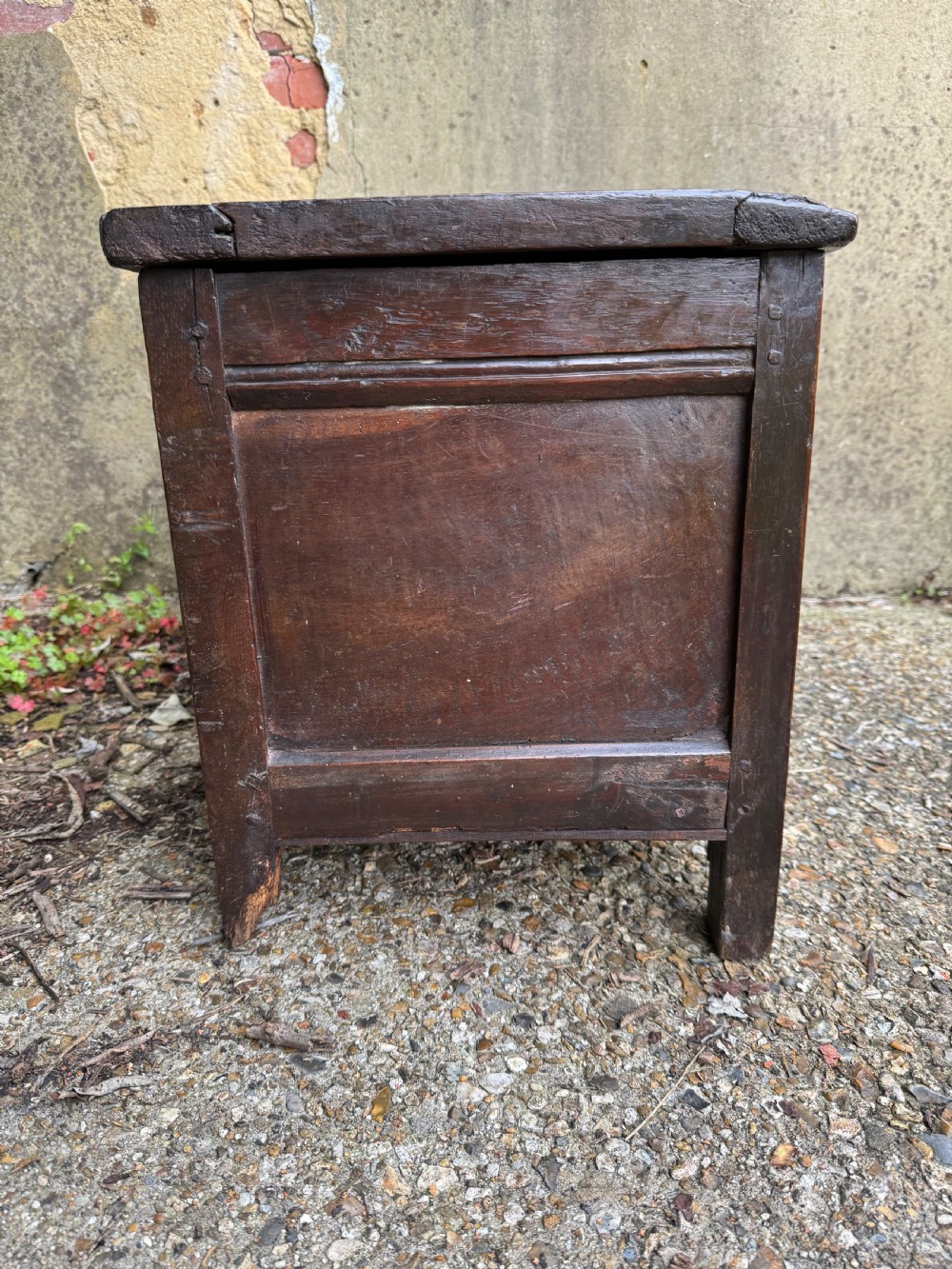 A small dark oak coffer featuring a carved top frieze, a three-panel front, and a central iron escutcheon. View IX