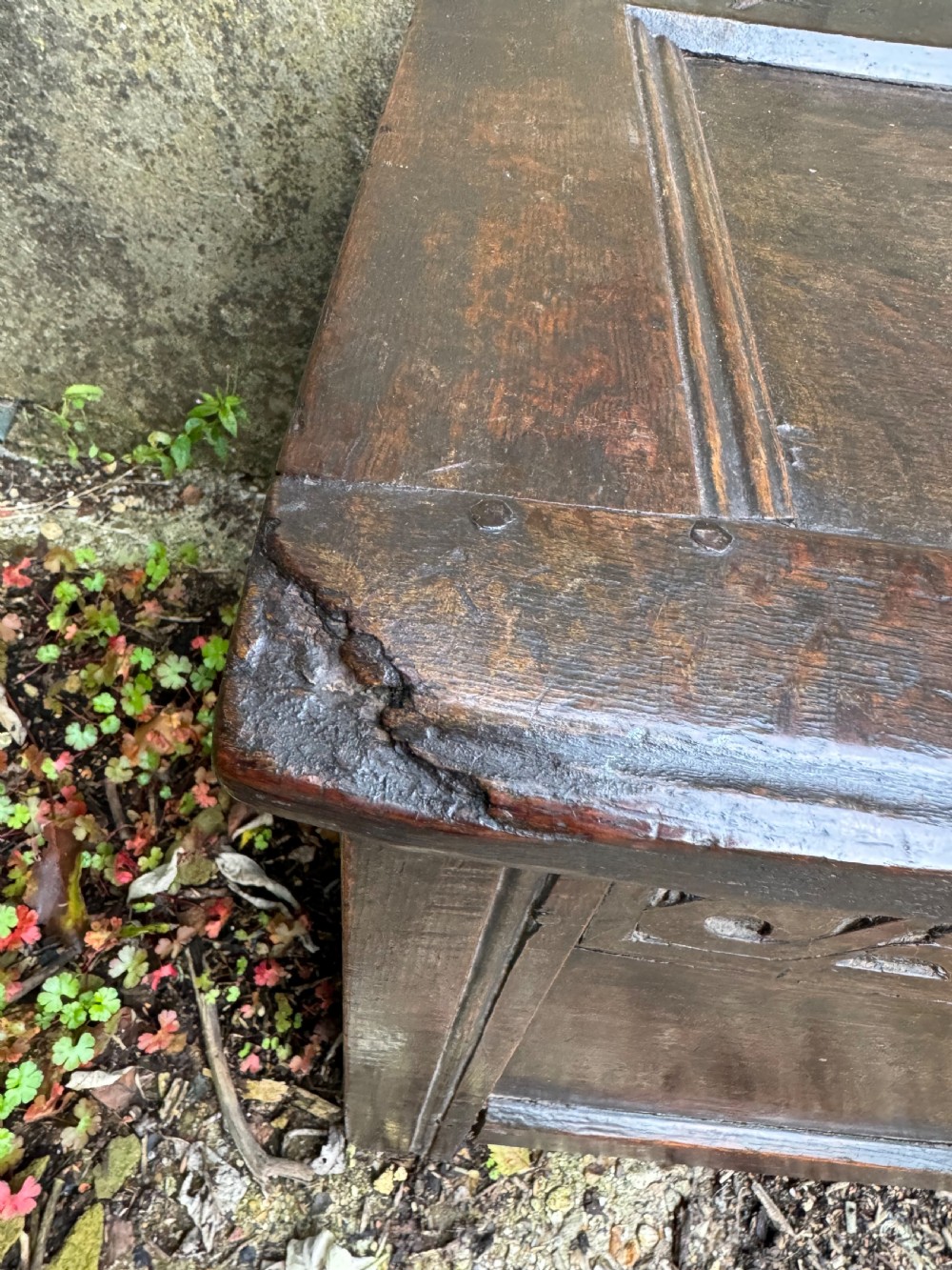 A small dark oak coffer featuring a carved top frieze, a three-panel front, and a central iron escutcheon. View XIV