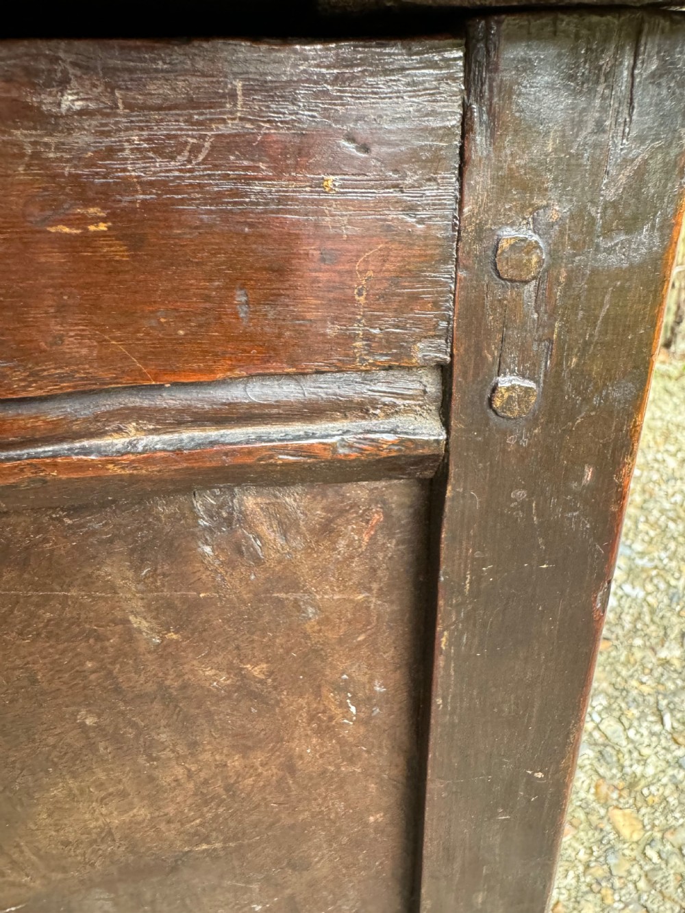 A small dark oak coffer featuring a carved top frieze, a three-panel front, and a central iron escutcheon. View XXI