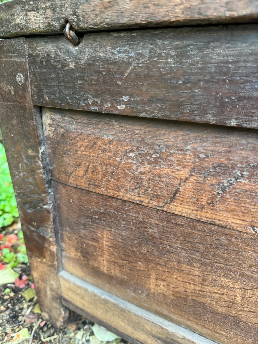 A small dark oak coffer featuring a carved top frieze, a three-panel front, and a central iron escutcheon. View XXII