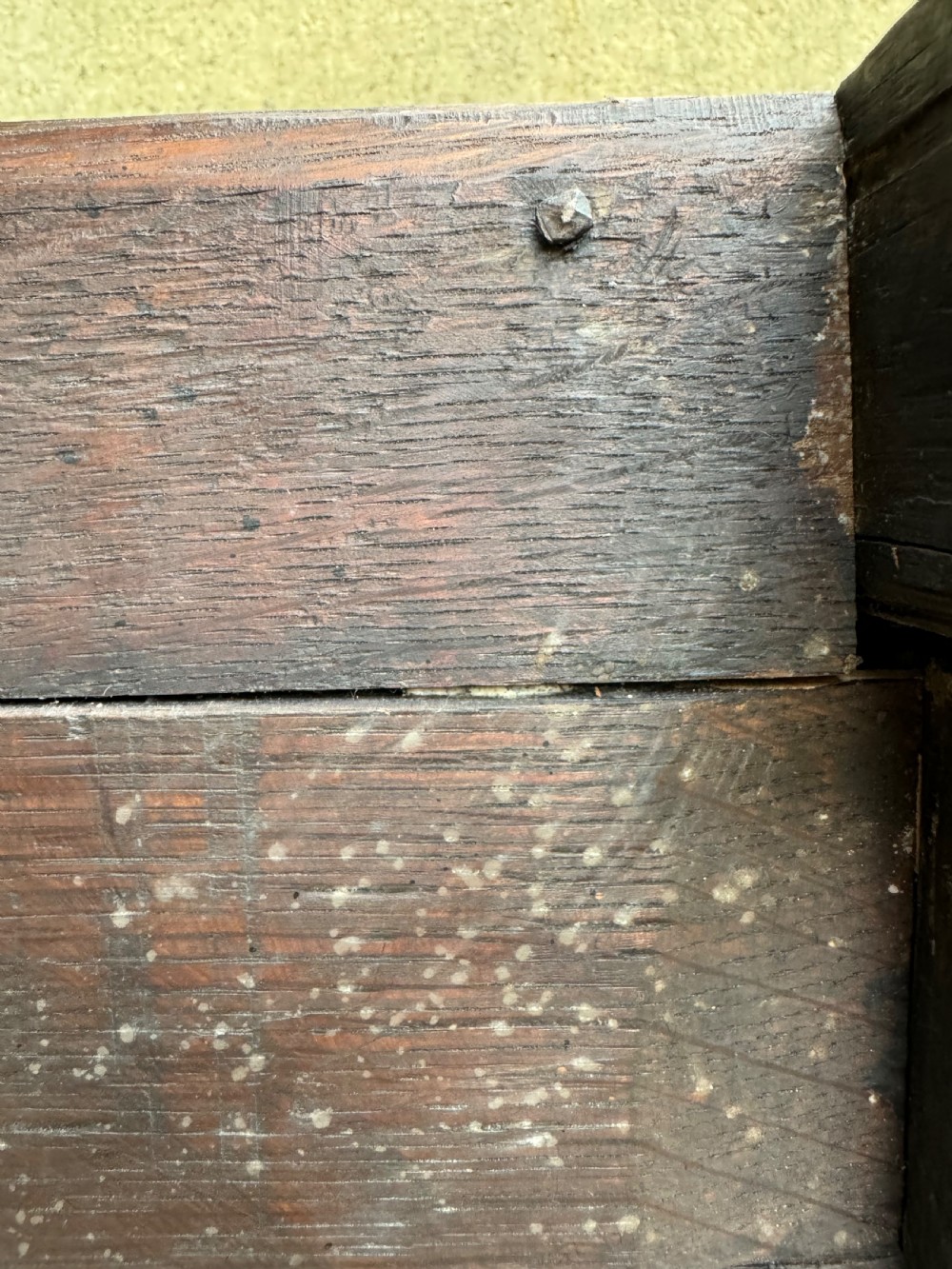 A small dark oak coffer featuring a carved top frieze, a three-panel front, and a central iron escutcheon. View XXVIII
