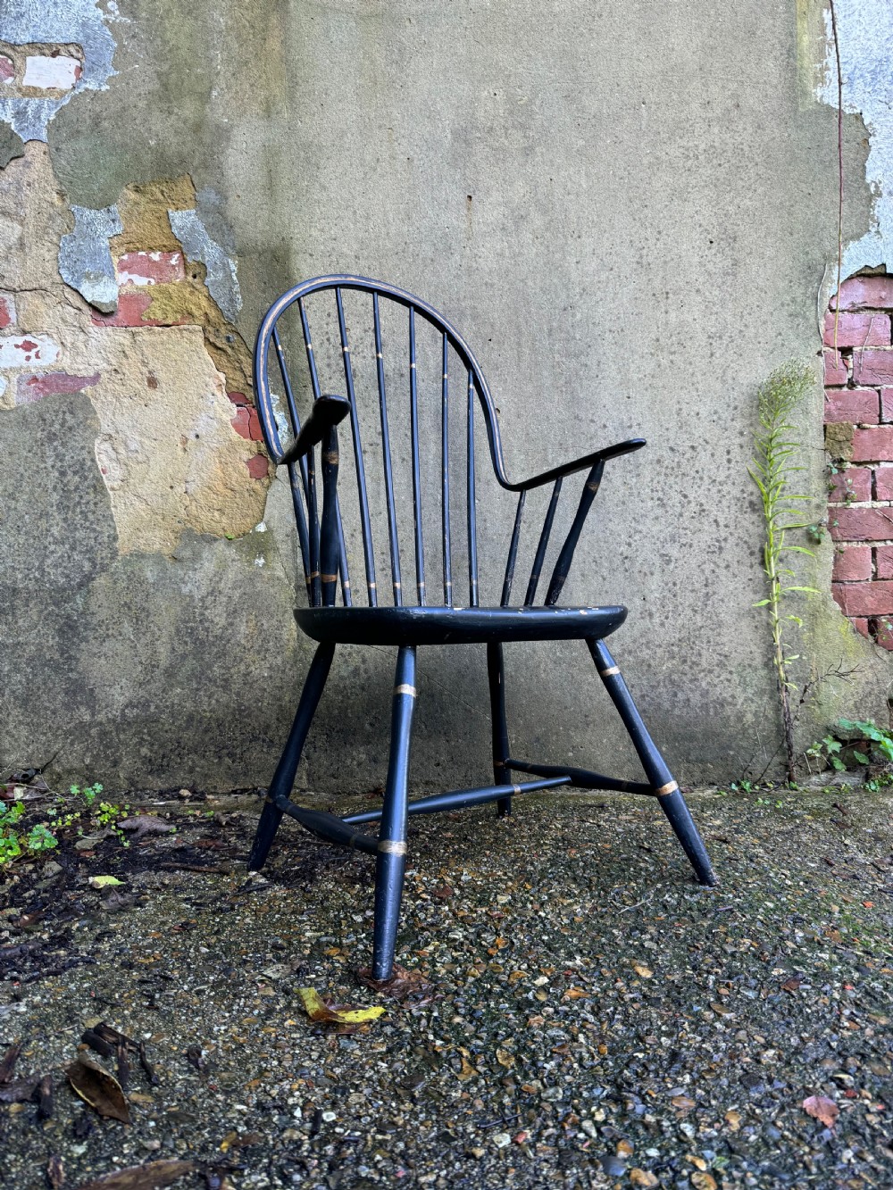 A black-painted wooden Windsor armchair featuring a hoop back with vertical spindles, curved armrests, and turned legs joined by stretchers.