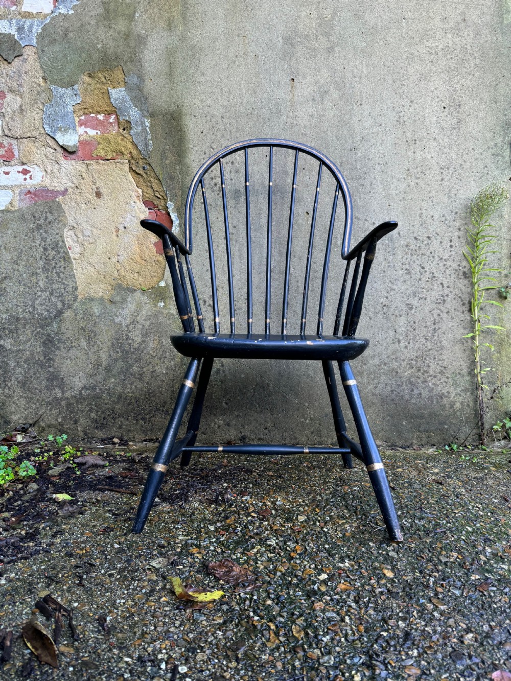 A black-painted wooden Windsor armchair featuring a hoop back with vertical spindles, curved armrests, and turned legs joined by stretchers. View III