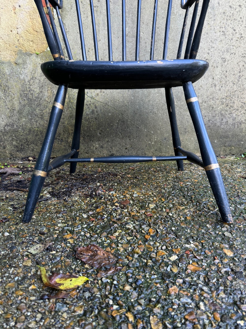 A black-painted wooden Windsor armchair featuring a hoop back with vertical spindles, curved armrests, and turned legs joined by stretchers. View VI