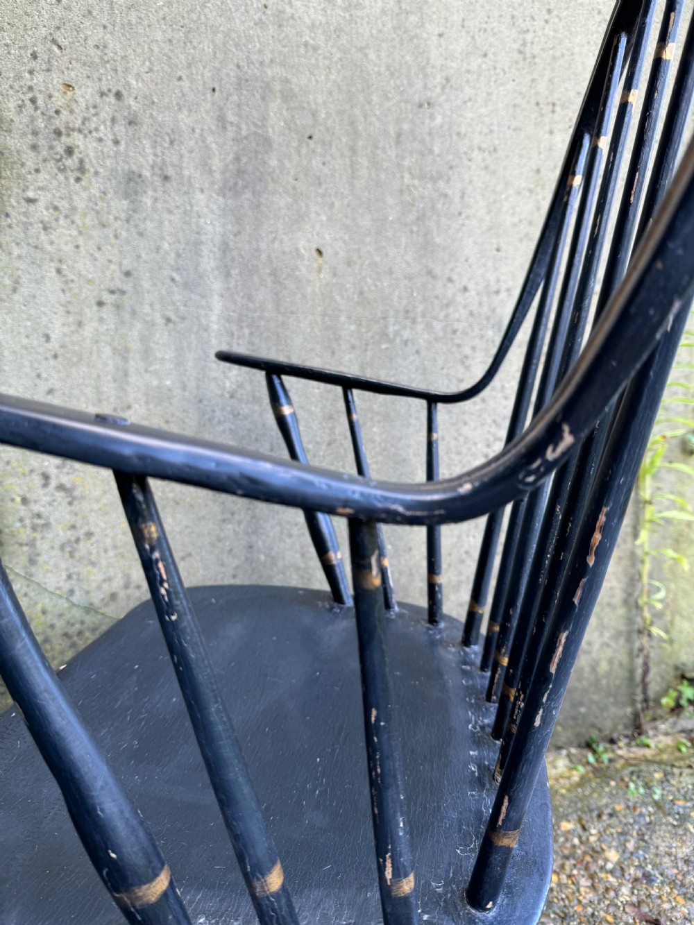 A black-painted wooden Windsor armchair featuring a hoop back with vertical spindles, curved armrests, and turned legs joined by stretchers. View XVI