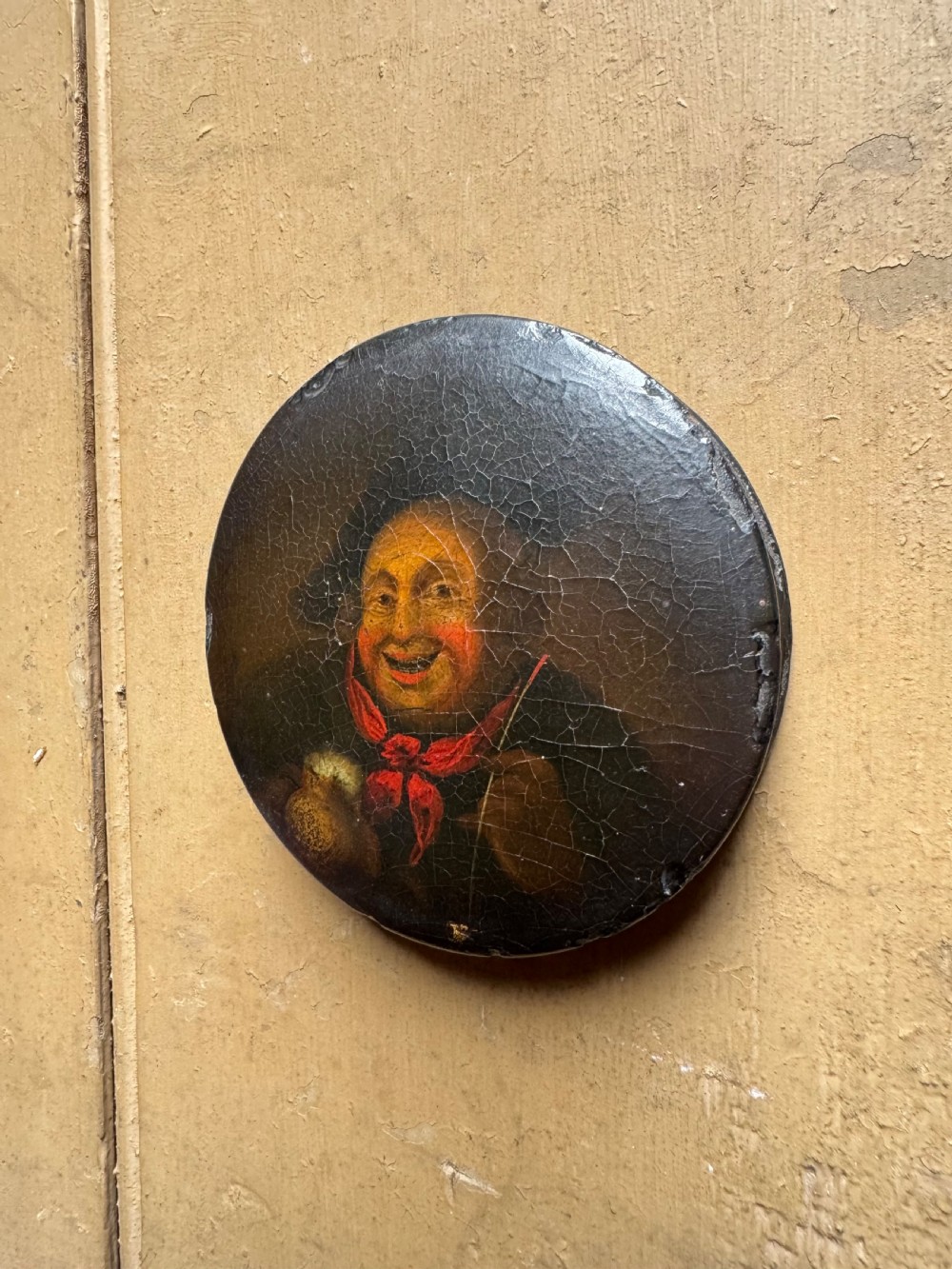 A circular antique lacquer portrait box lid depicting a smiling man with a red neckerchief featuring visible surface craquelure. View IV