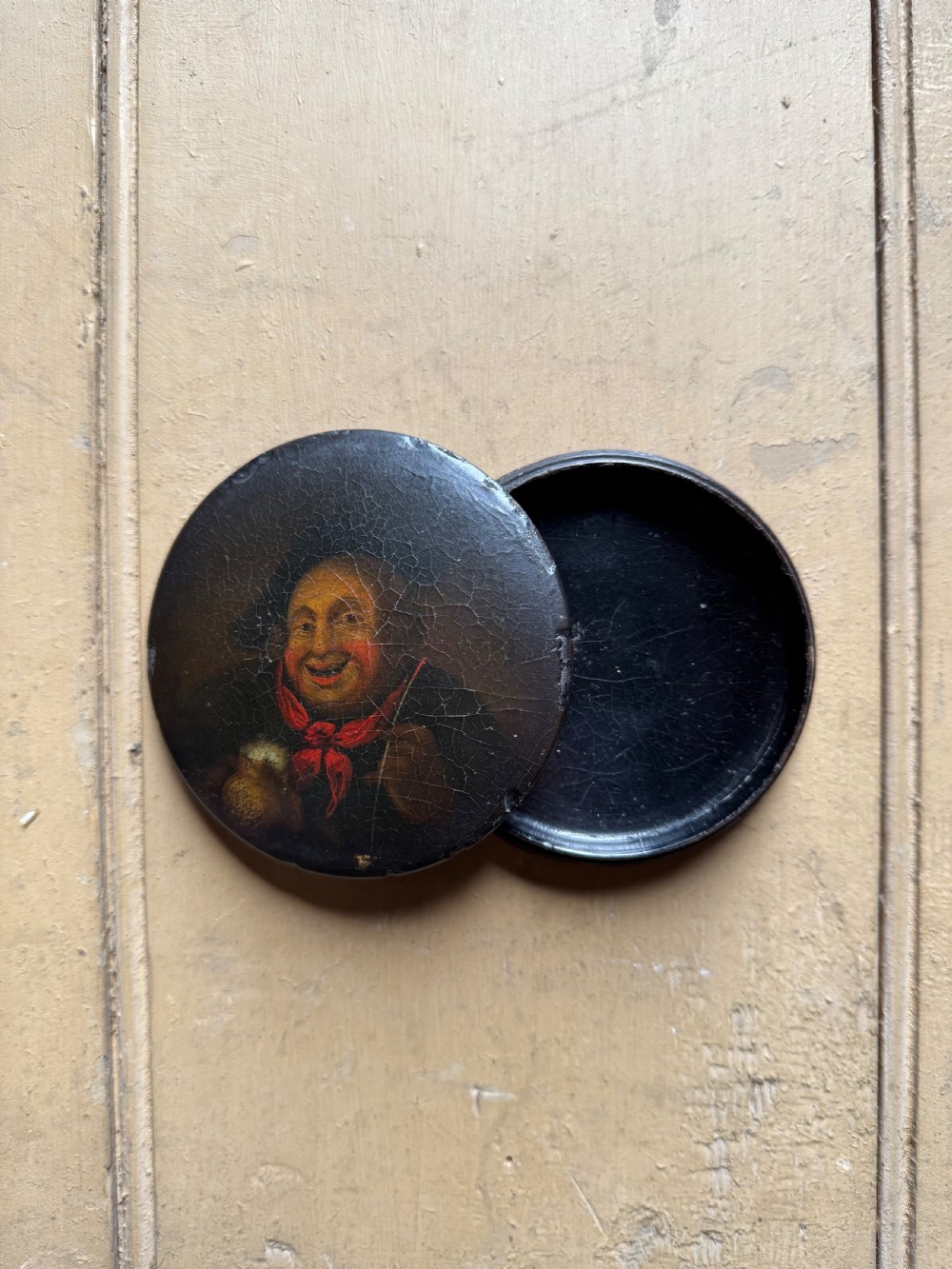 A circular antique lacquer portrait box lid depicting a smiling man with a red neckerchief featuring visible surface craquelure. View VI