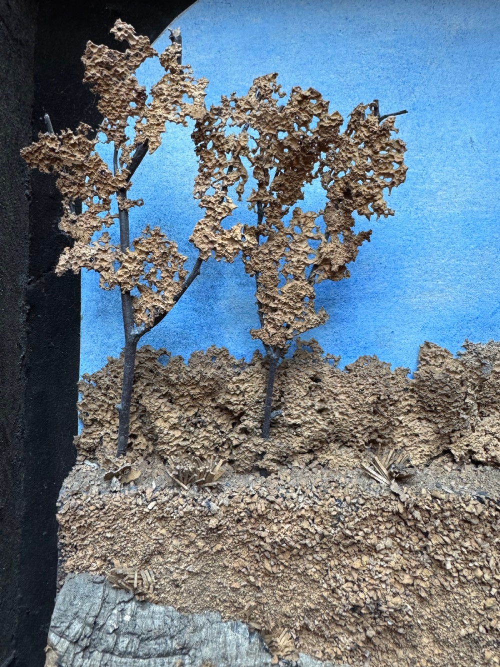 A framed nineteenth-century three-dimensional cork diorama depicting a castle on a hill against a painted light blue backdrop inside a glazed moulded frame. View VI