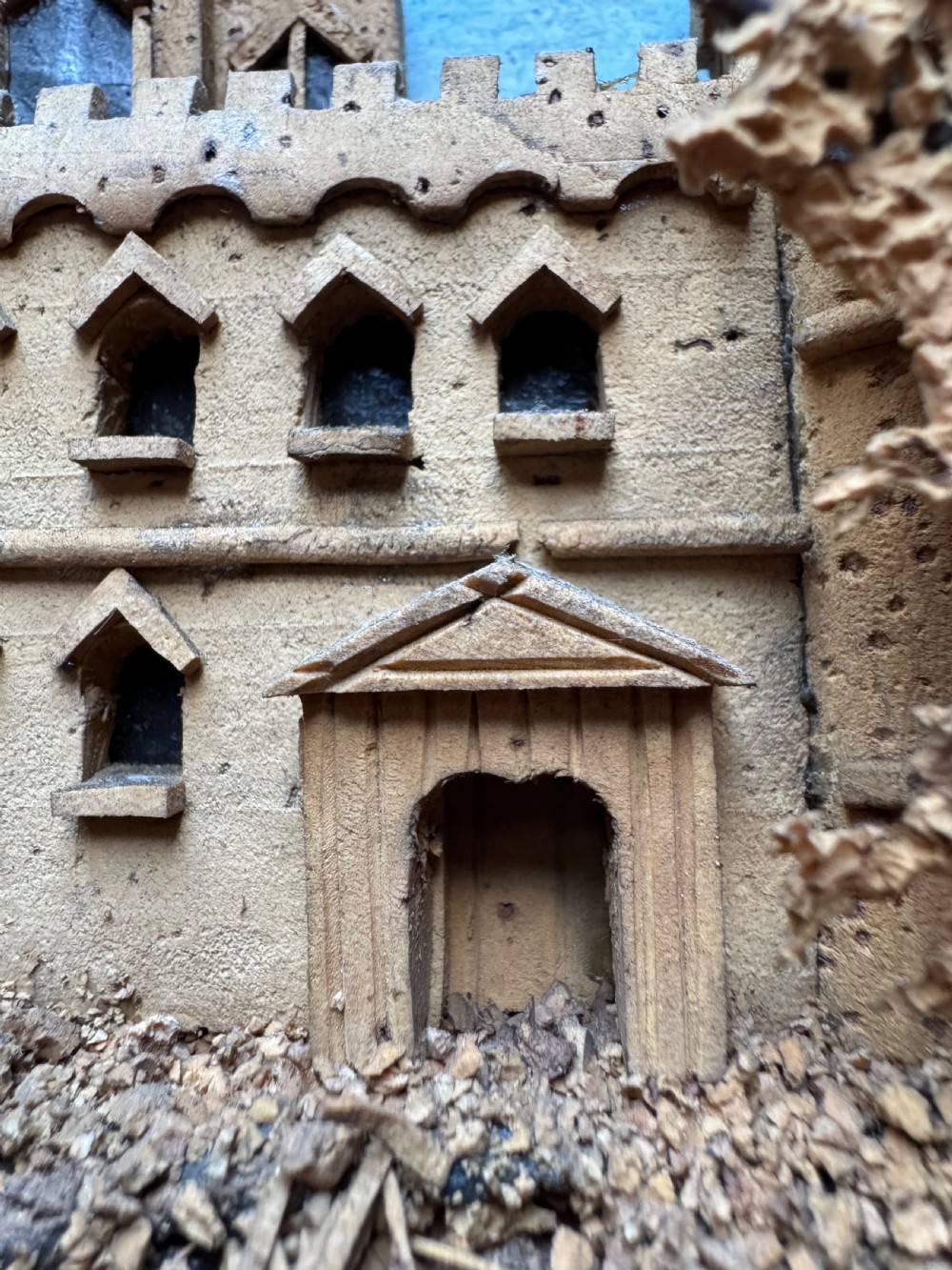 A framed nineteenth-century three-dimensional cork diorama depicting a castle on a hill against a painted light blue backdrop inside a glazed moulded frame. View IX