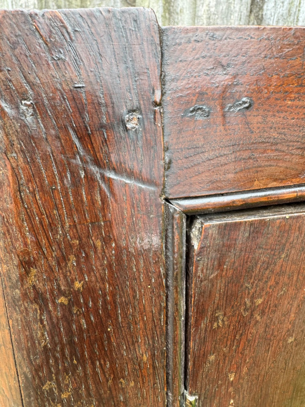 An antique dark oak provincial cupboard featuring canted sides, a single panelled door, a wooden knob, and an iron keyhole escutcheon. View XII