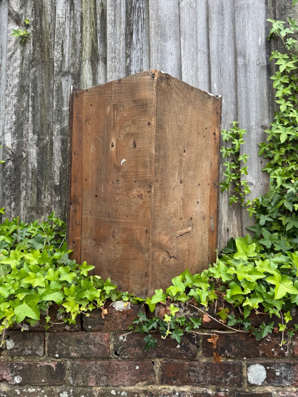 An antique dark oak provincial cupboard featuring canted sides, a single panelled door, a wooden knob, and an iron keyhole escutcheon. View XV