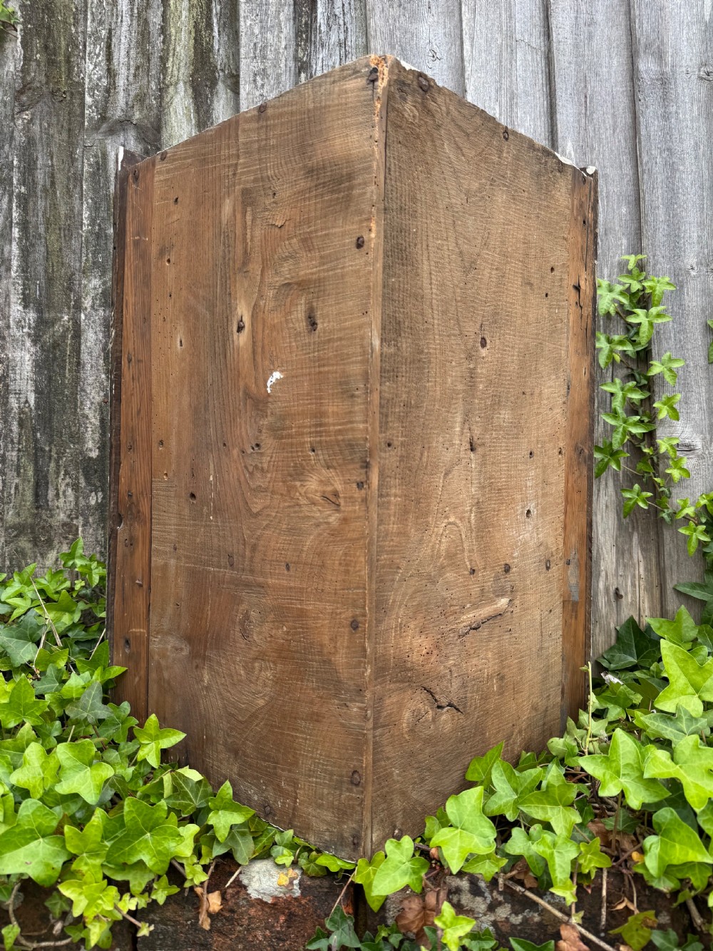 An antique dark oak provincial cupboard featuring canted sides, a single panelled door, a wooden knob, and an iron keyhole escutcheon. View XVI