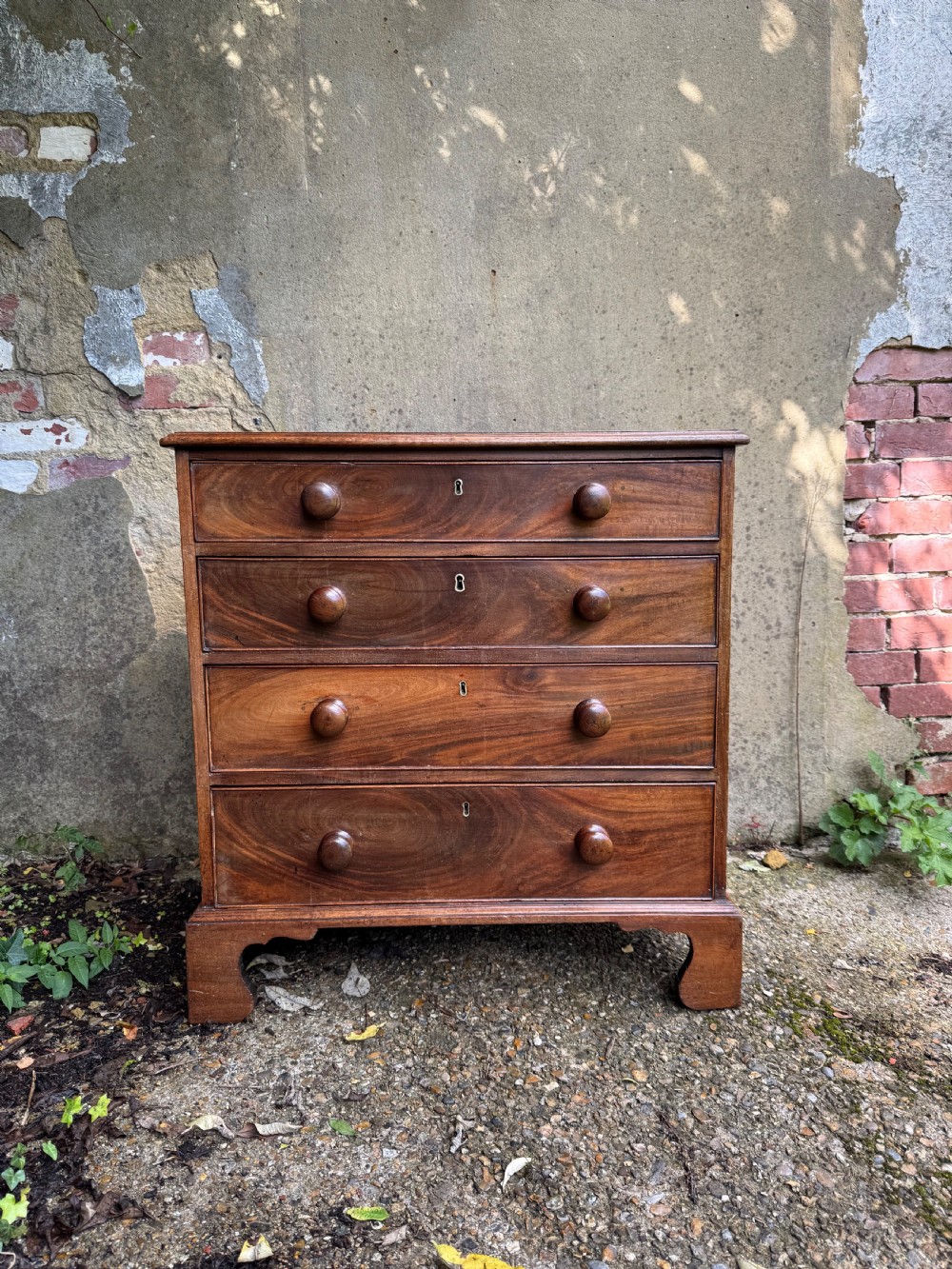 A Georgian mahogany chest featuring four graduated drawers with turned wooden knobs, keyhole escutcheons, and classic bracket feet.