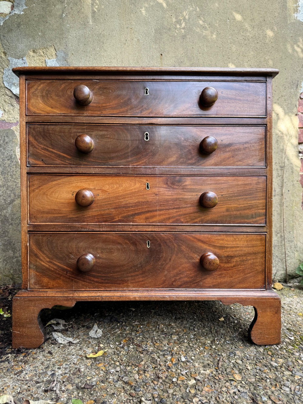 A Georgian mahogany chest featuring four graduated drawers with turned wooden knobs, keyhole escutcheons, and classic bracket feet. View II