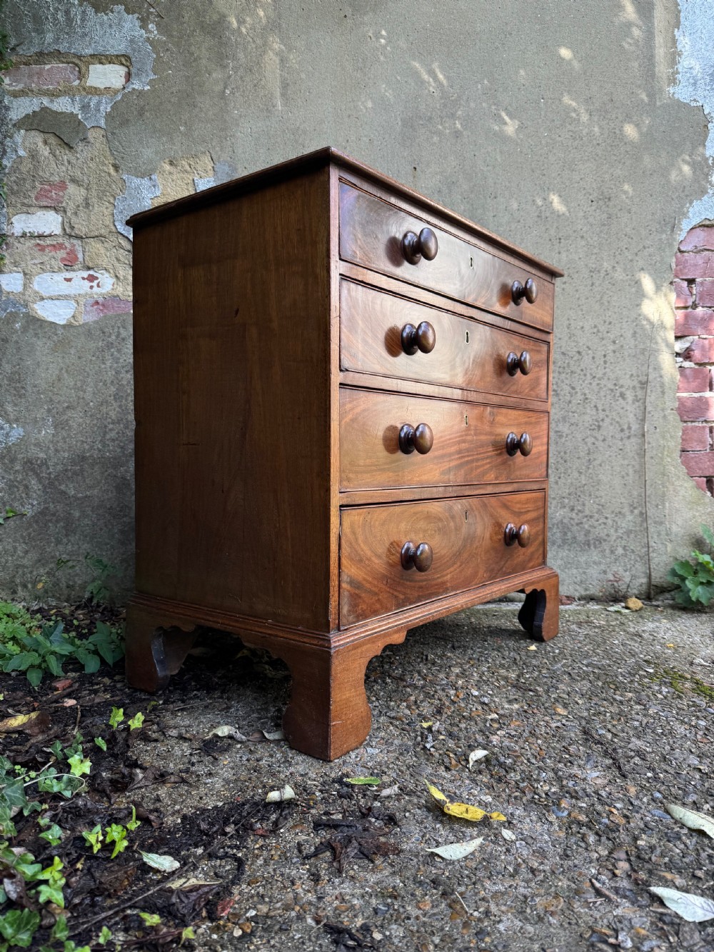A Georgian mahogany chest featuring four graduated drawers with turned wooden knobs, keyhole escutcheons, and classic bracket feet. View III