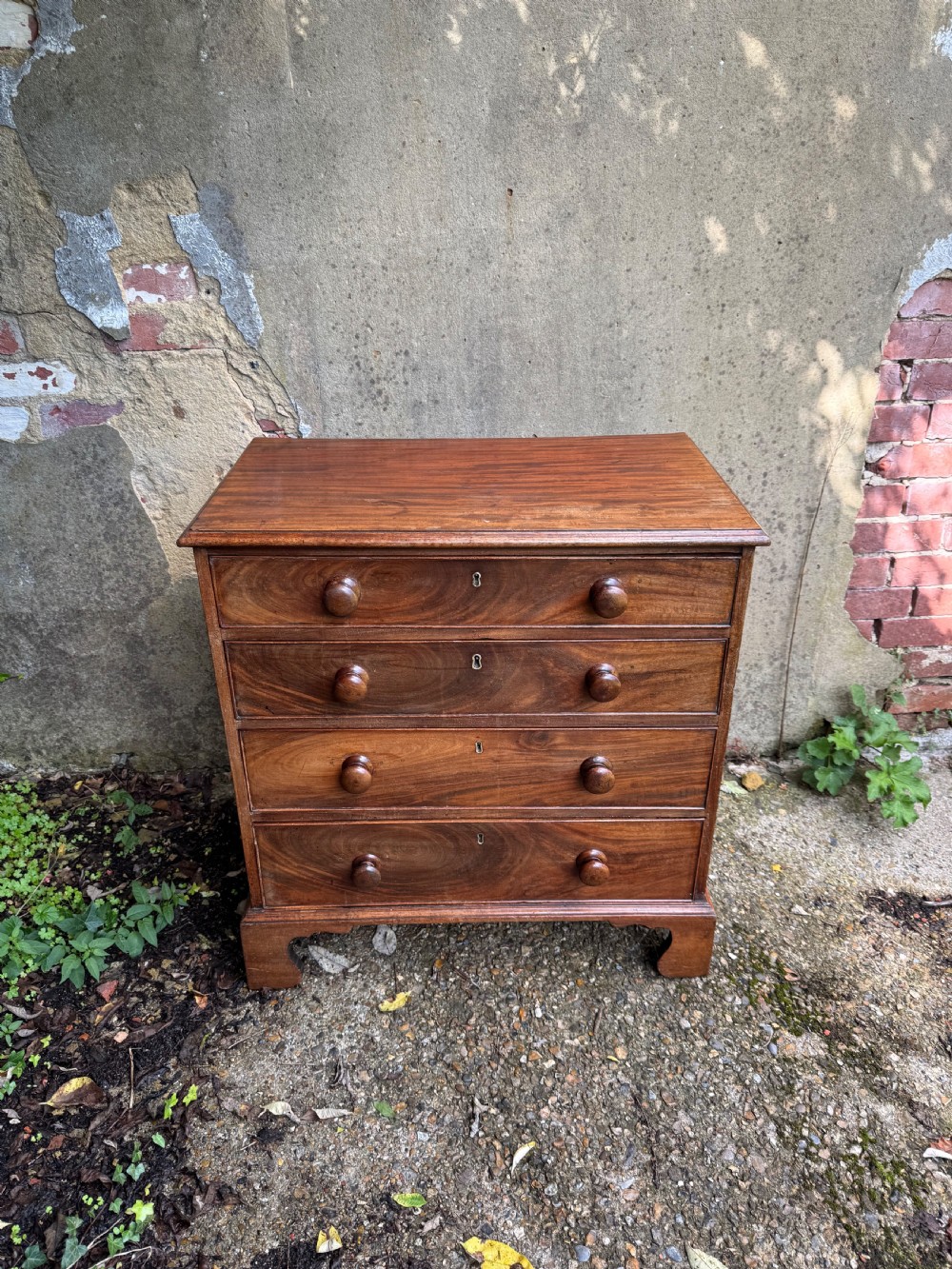 A Georgian mahogany chest featuring four graduated drawers with turned wooden knobs, keyhole escutcheons, and classic bracket feet. View VI