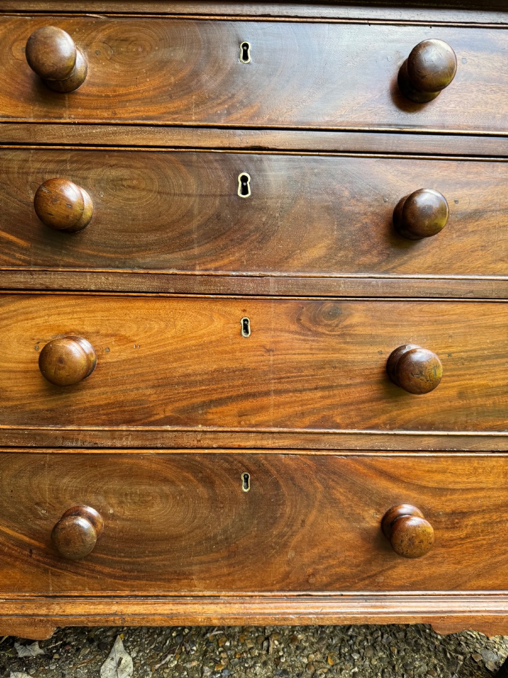 A Georgian mahogany chest featuring four graduated drawers with turned wooden knobs, keyhole escutcheons, and classic bracket feet. View VIII