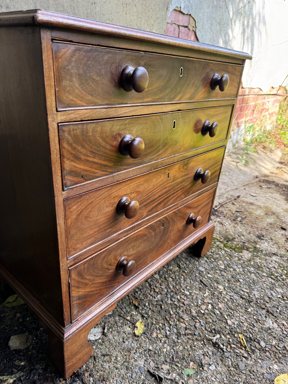 A Georgian mahogany chest featuring four graduated drawers with turned wooden knobs, keyhole escutcheons, and classic bracket feet. View XIII