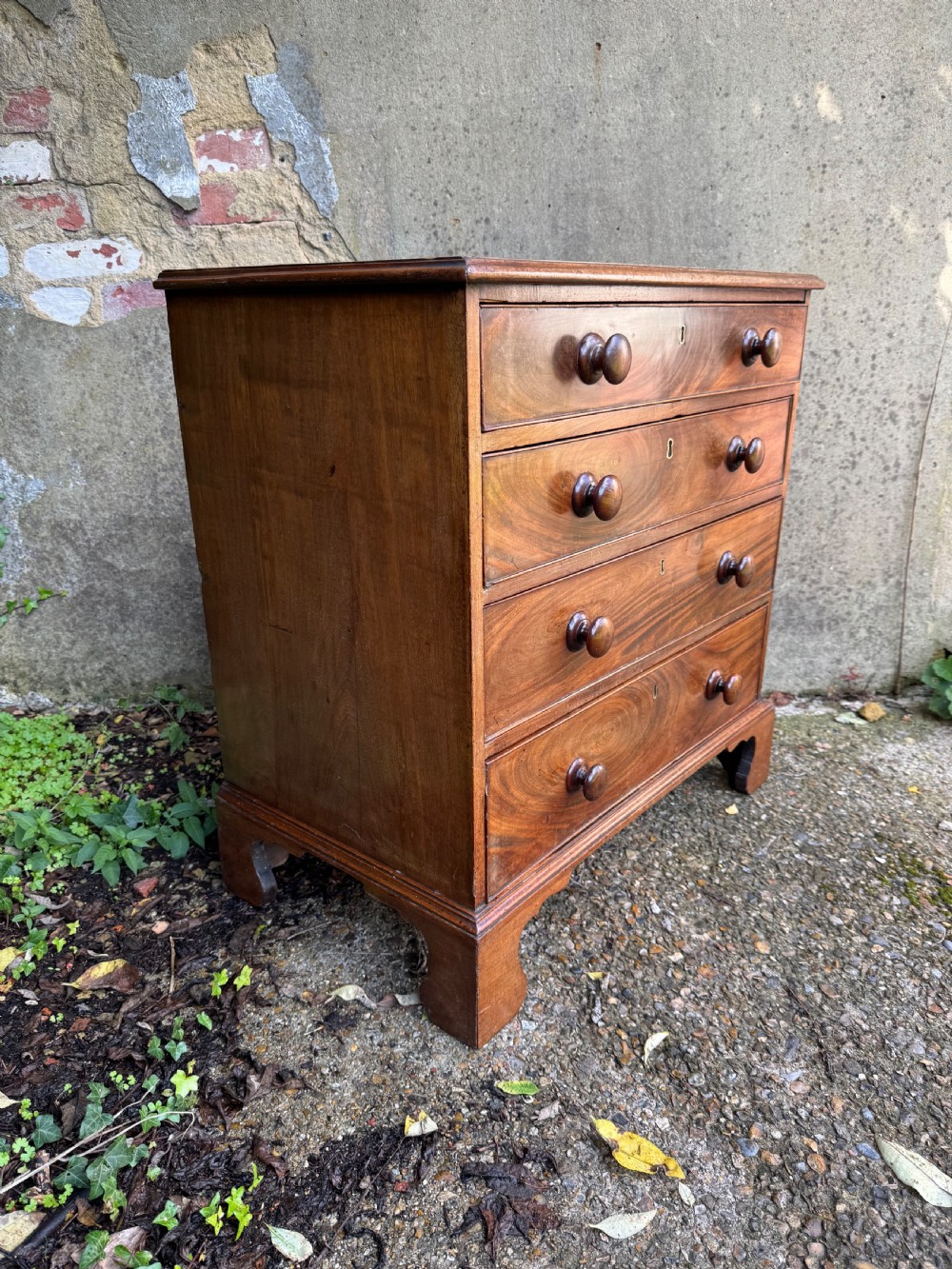 A Georgian mahogany chest featuring four graduated drawers with turned wooden knobs, keyhole escutcheons, and classic bracket feet. View XV