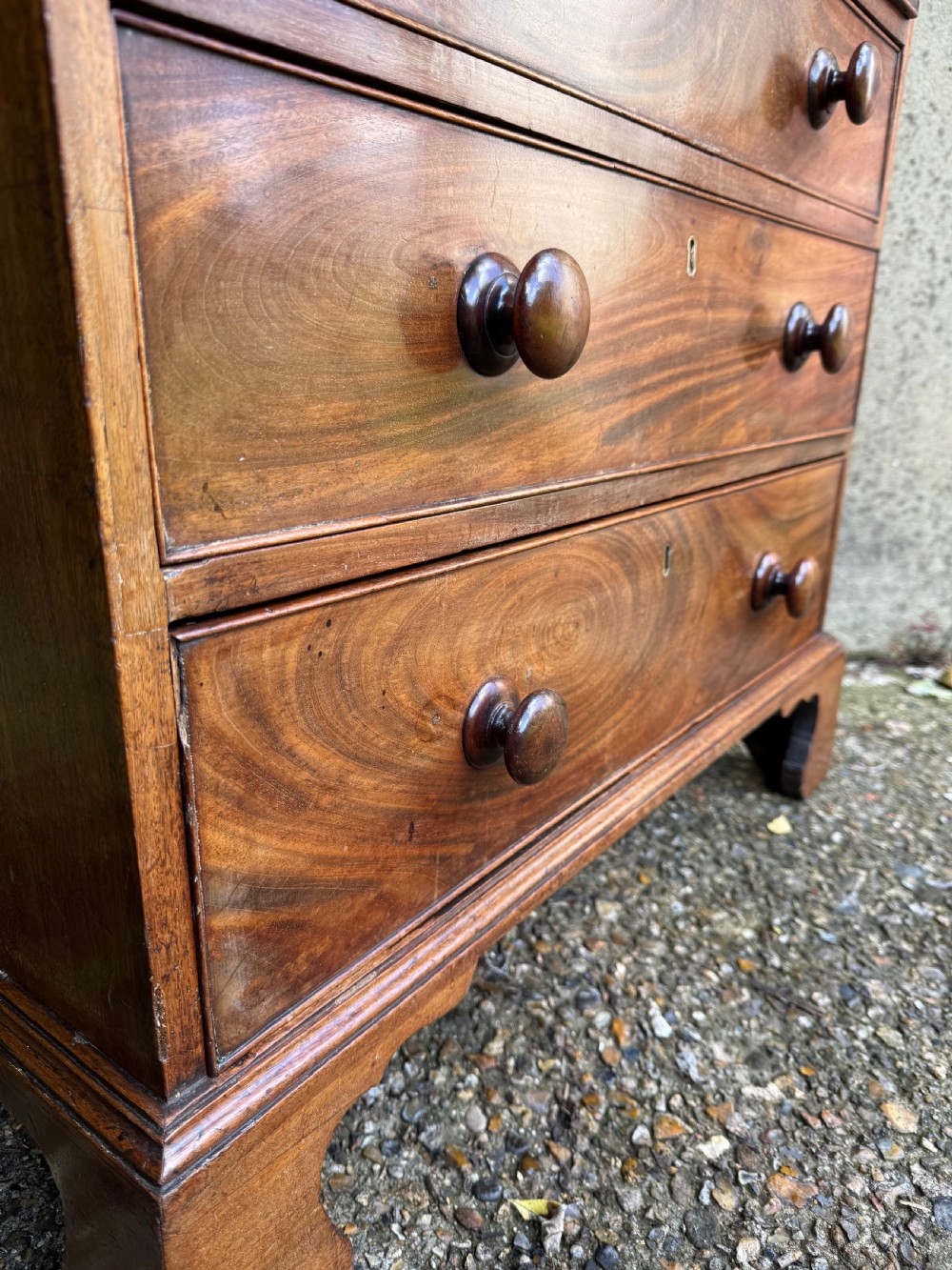 A Georgian mahogany chest featuring four graduated drawers with turned wooden knobs, keyhole escutcheons, and classic bracket feet. View XVII