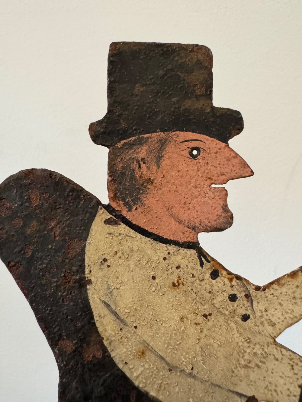 A painted metal folk art figure depicting a sawyer wearing a top hat and holding a serrated saw with aged paint loss and oxidised patina. View II