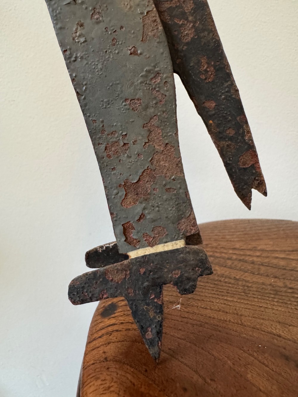 A painted metal folk art figure depicting a sawyer wearing a top hat and holding a serrated saw with aged paint loss and oxidised patina. View VII