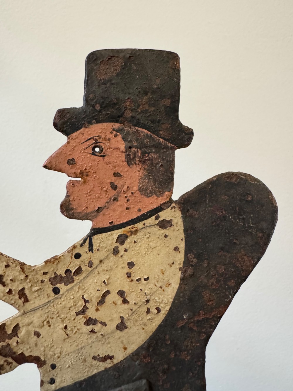 A painted metal folk art figure depicting a sawyer wearing a top hat and holding a serrated saw with aged paint loss and oxidised patina. View IX
