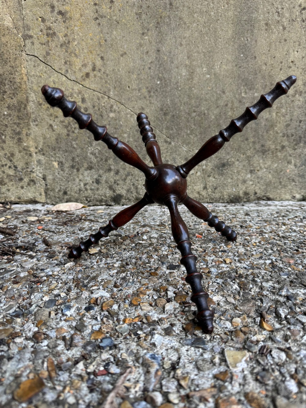 A dark turned wooden cat stand featuring six turned spindle legs radiating from a central sphere.