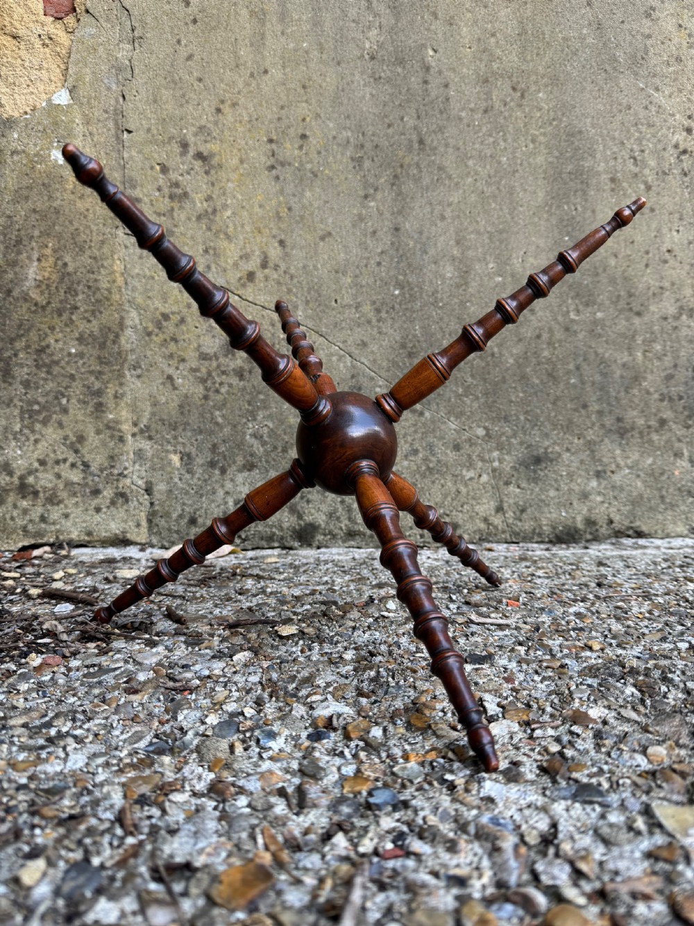 A dark turned wood six-spoked cat stand featuring bobbin-style spindle legs radiating from a central spherical hub.