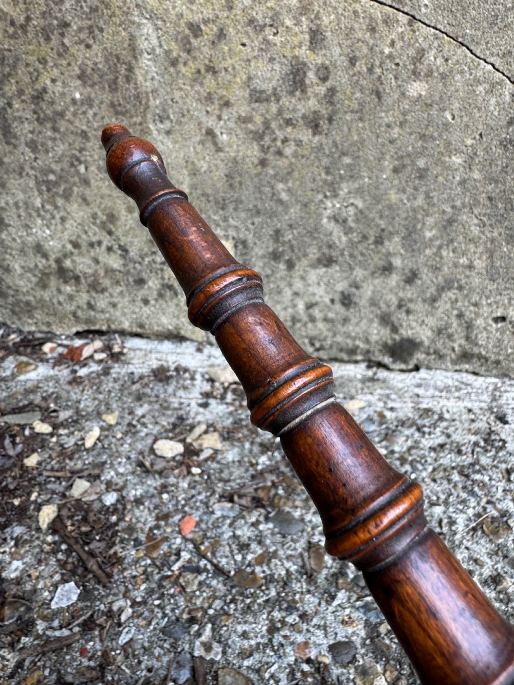 A dark turned wood six-spoked cat stand featuring bobbin-style spindle legs radiating from a central spherical hub. View III