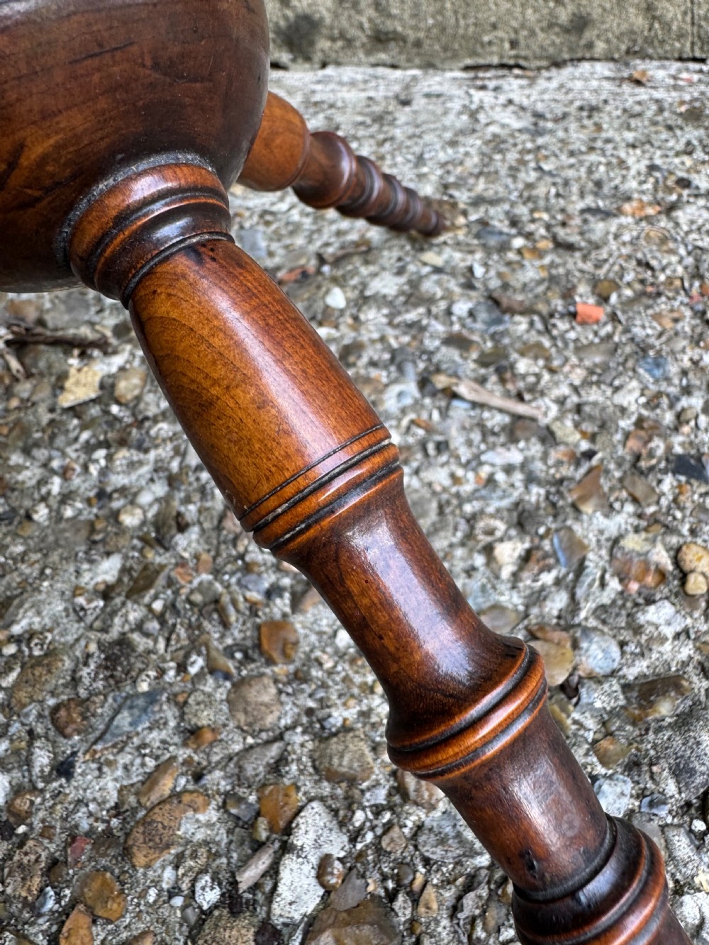 A dark turned wood six-spoked cat stand featuring bobbin-style spindle legs radiating from a central spherical hub. View V