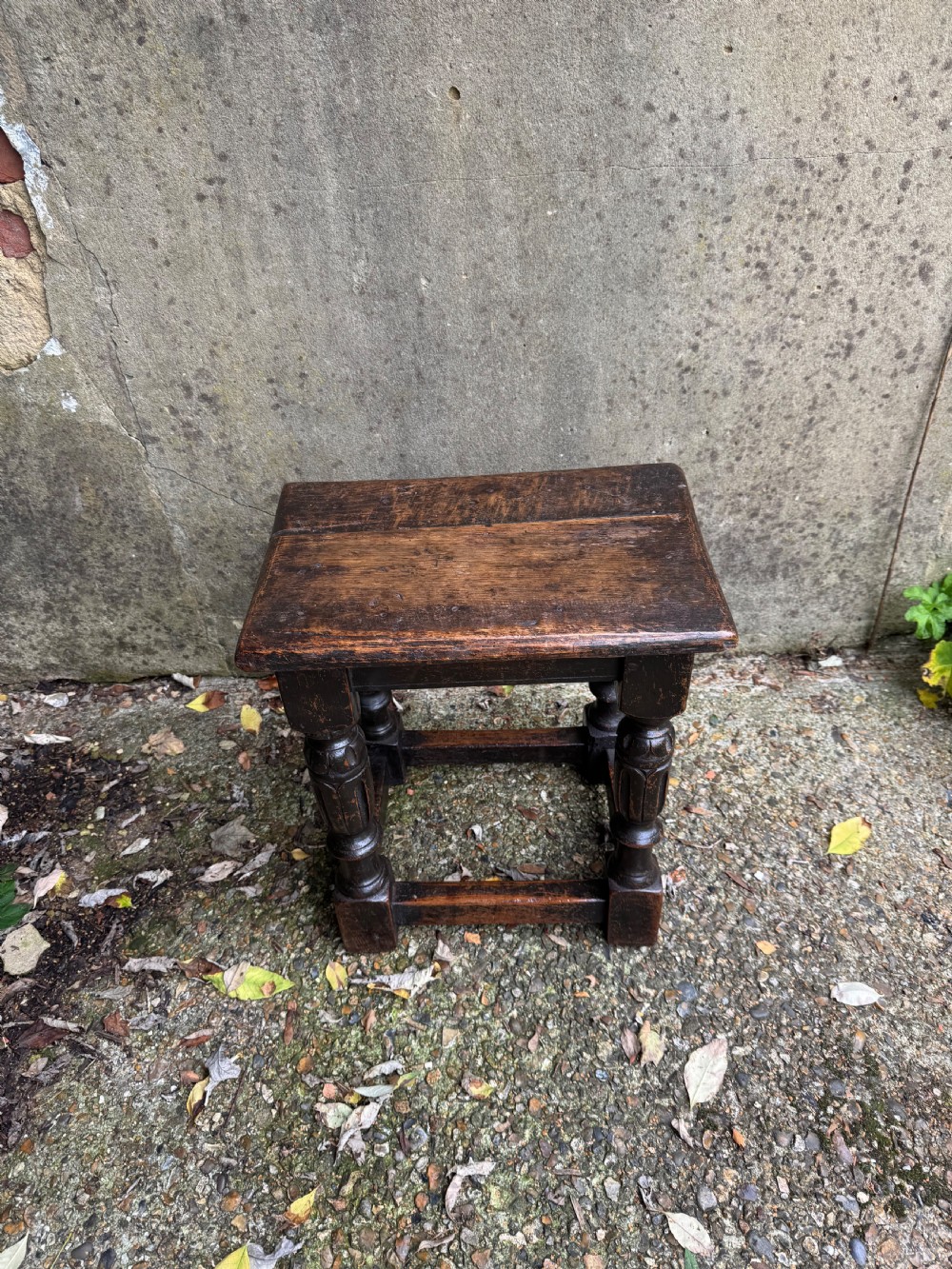 A dark oak joint stool featuring turned baluster legs, lower perimeter stretchers, and a flat rectangular top. View V