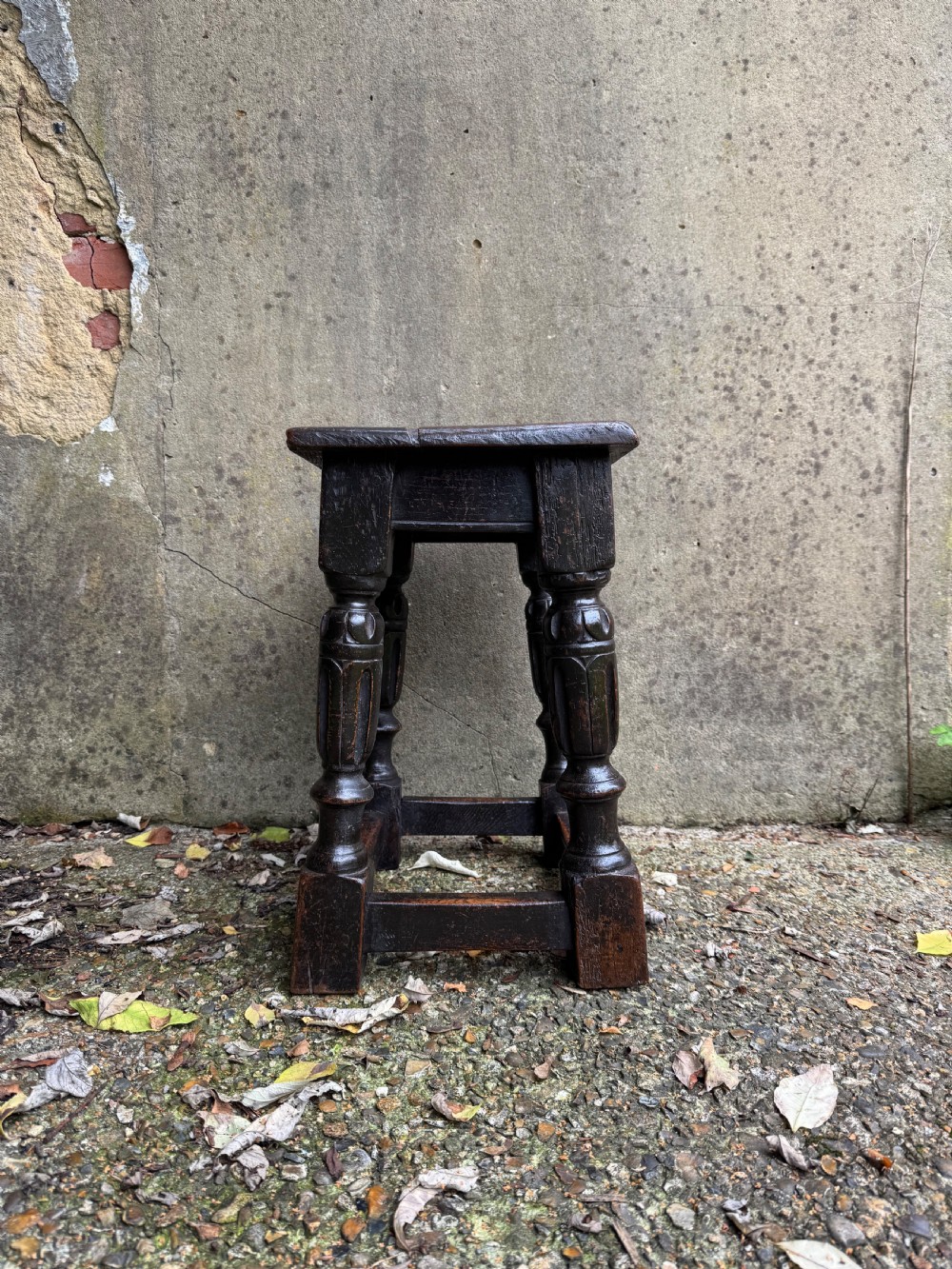 A dark oak joint stool featuring turned baluster legs, lower perimeter stretchers, and a flat rectangular top. View X