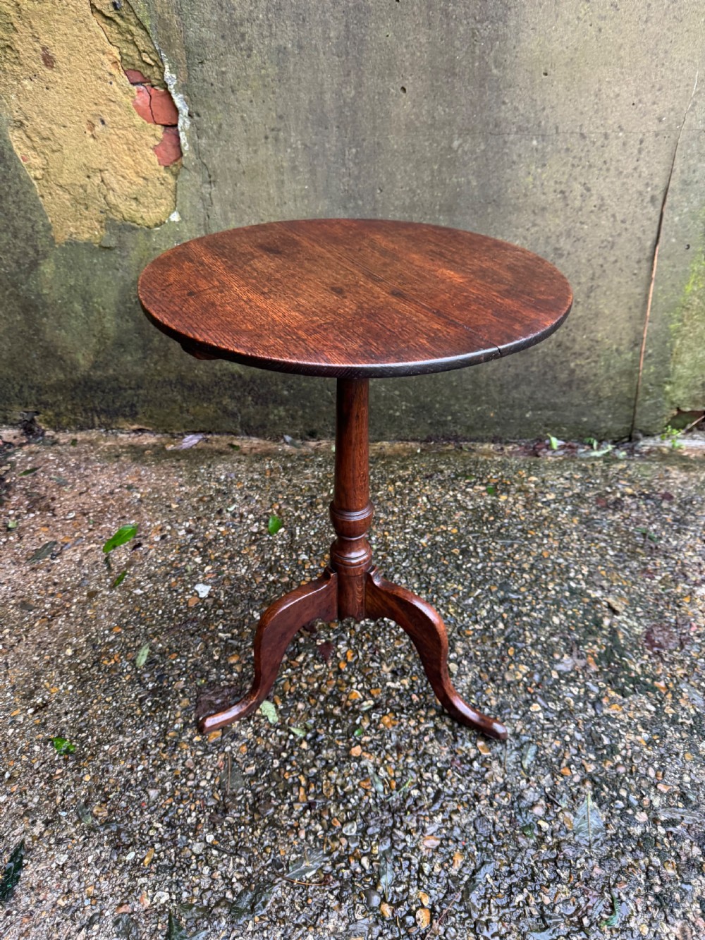 An antique dark oak circular tripod table with a turned central stem, three pad-foot legs, and a tilt-top mechanism. View VIII