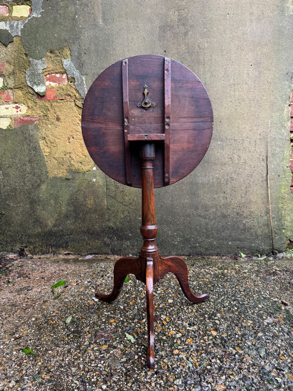 An antique dark oak circular tripod table with a turned central stem, three pad-foot legs, and a tilt-top mechanism. View IX
