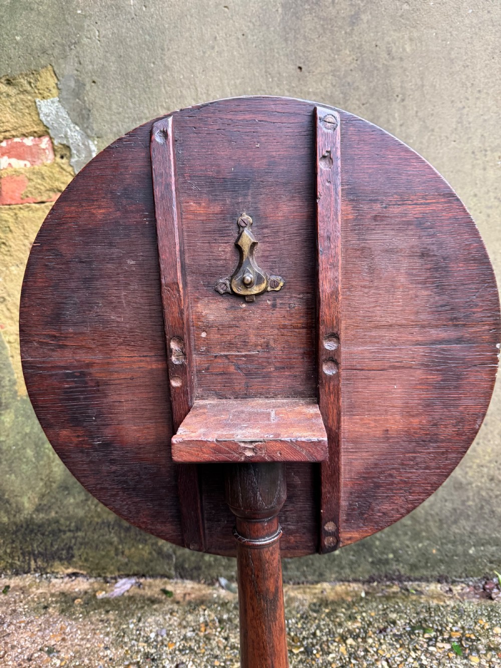 An antique dark oak circular tripod table with a turned central stem, three pad-foot legs, and a tilt-top mechanism. View X