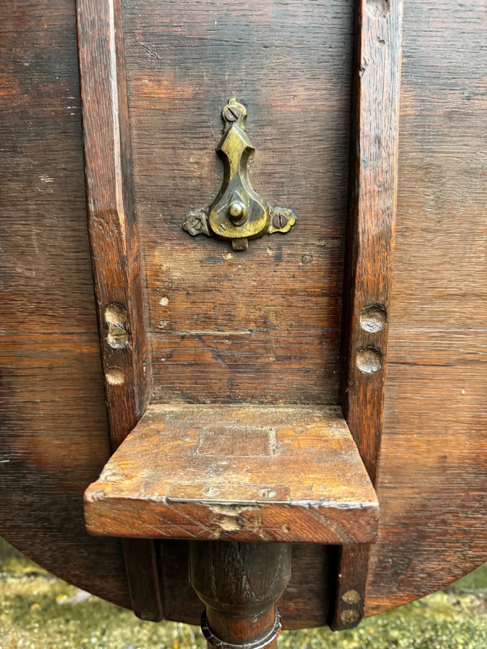 An antique dark oak circular tripod table with a turned central stem, three pad-foot legs, and a tilt-top mechanism. View XI