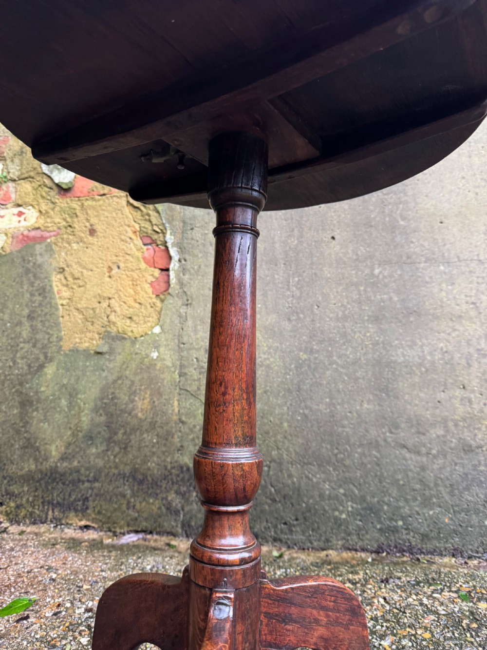 An antique dark oak circular tripod table with a turned central stem, three pad-foot legs, and a tilt-top mechanism. View XIV