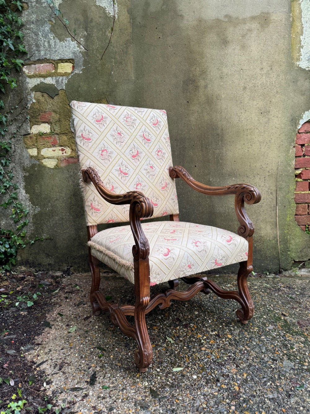 A French style carved walnut armchair featuring a tall backrest, scrolled armrests, patterned cream and pink upholstery, and intricately carved legs. View III