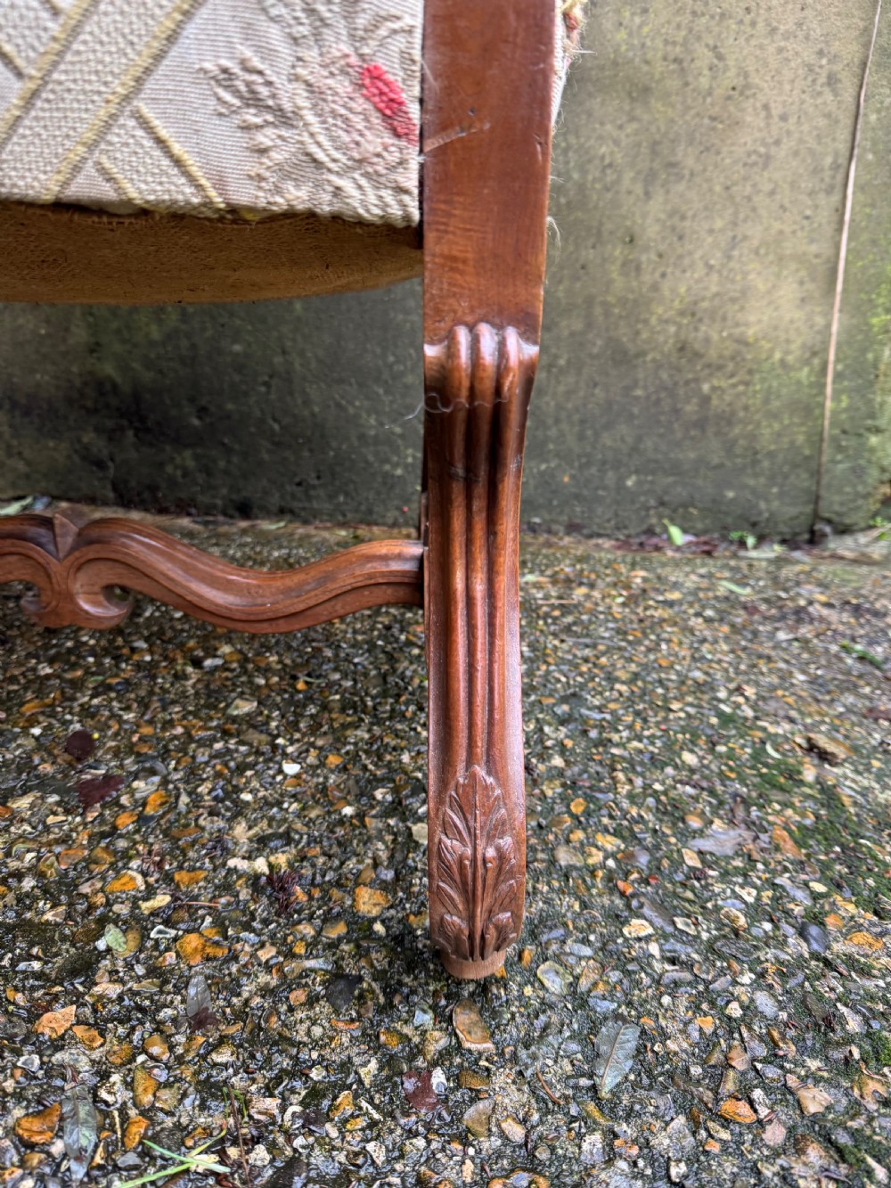 A French style carved walnut armchair featuring a tall backrest, scrolled armrests, patterned cream and pink upholstery, and intricately carved legs. View VII