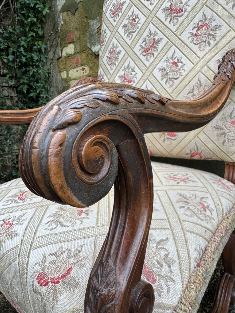 A French style carved walnut armchair featuring a tall backrest, scrolled armrests, patterned cream and pink upholstery, and intricately carved legs. View VIII