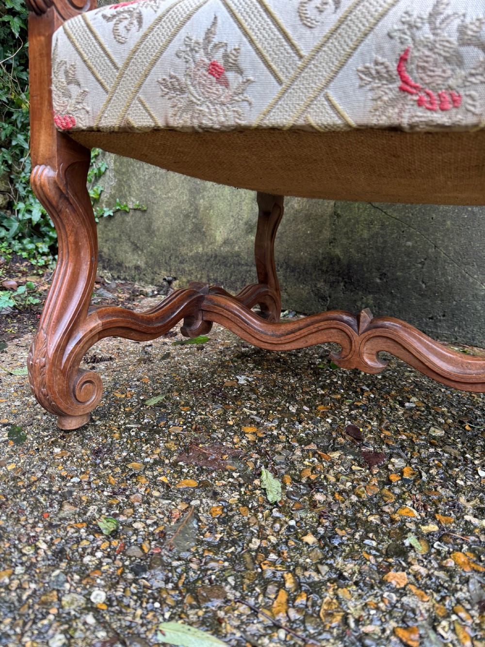 A French style carved walnut armchair featuring a tall backrest, scrolled armrests, patterned cream and pink upholstery, and intricately carved legs. View IX