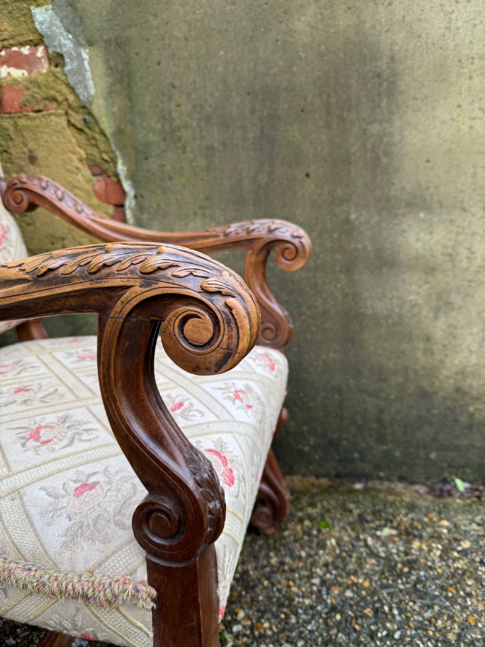 A French style carved walnut armchair featuring a tall backrest, scrolled armrests, patterned cream and pink upholstery, and intricately carved legs. View XIII