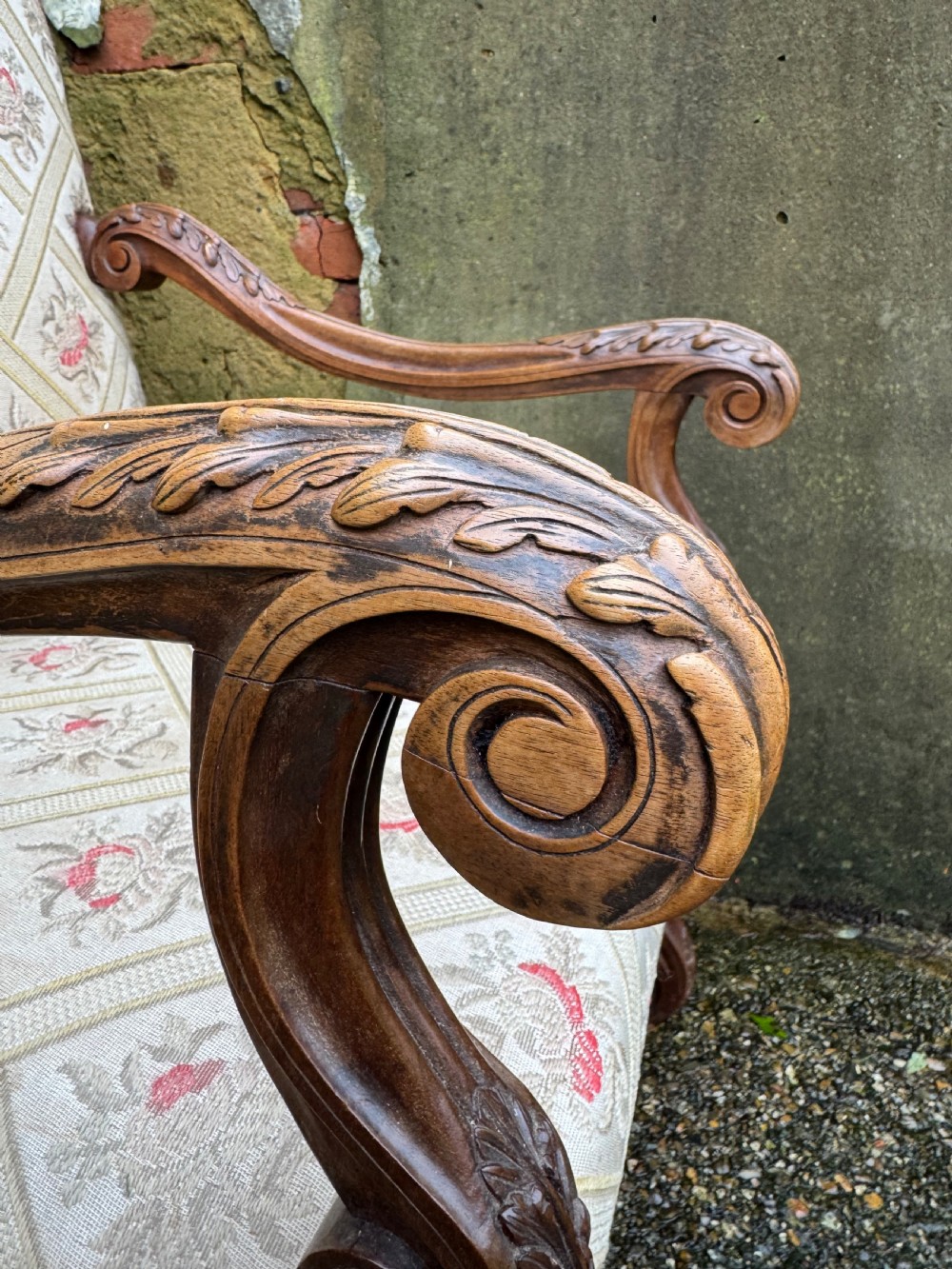 A French style carved walnut armchair featuring a tall backrest, scrolled armrests, patterned cream and pink upholstery, and intricately carved legs. View XIV