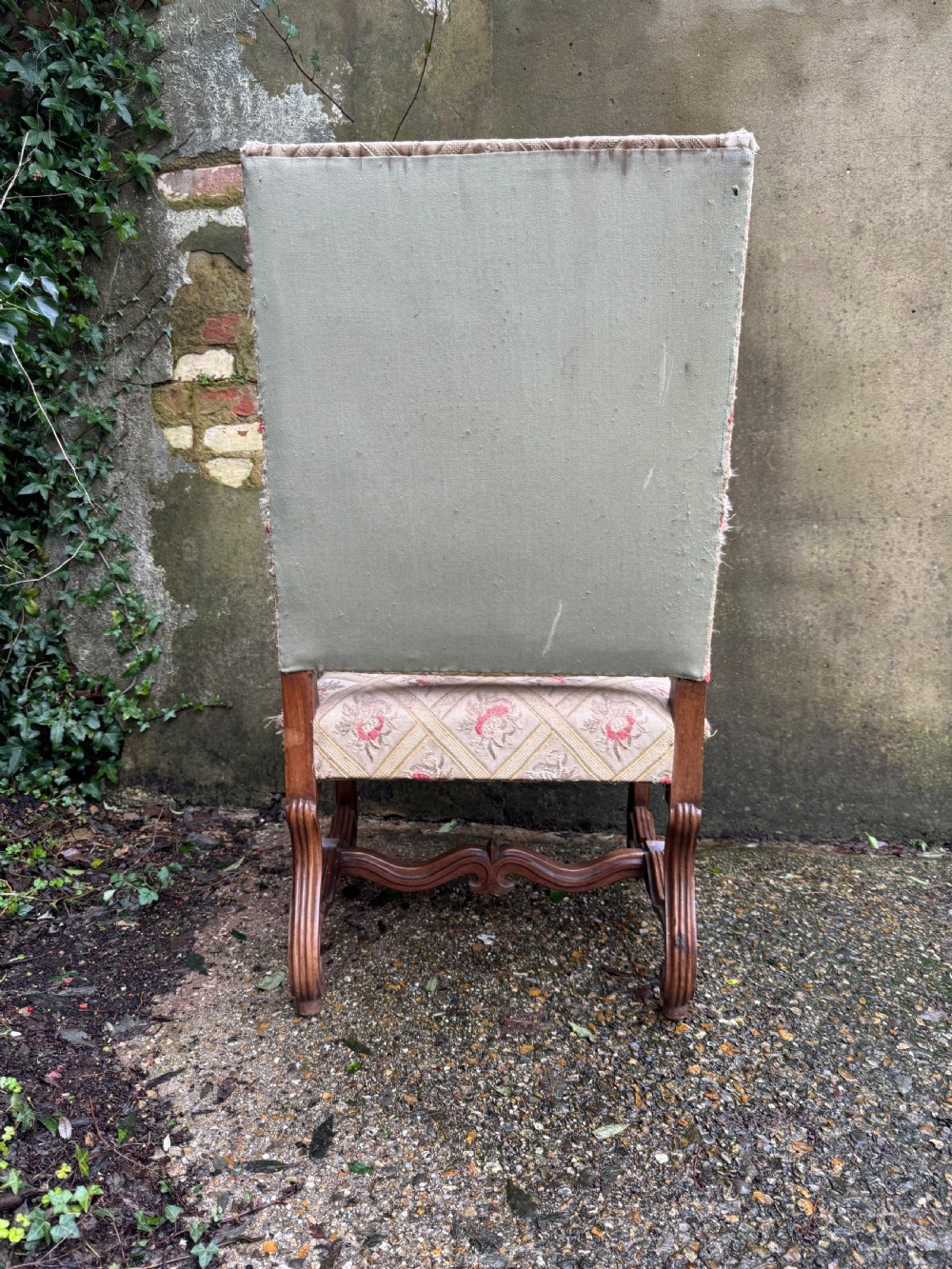 A French style carved walnut armchair featuring a tall backrest, scrolled armrests, patterned cream and pink upholstery, and intricately carved legs. View XVI