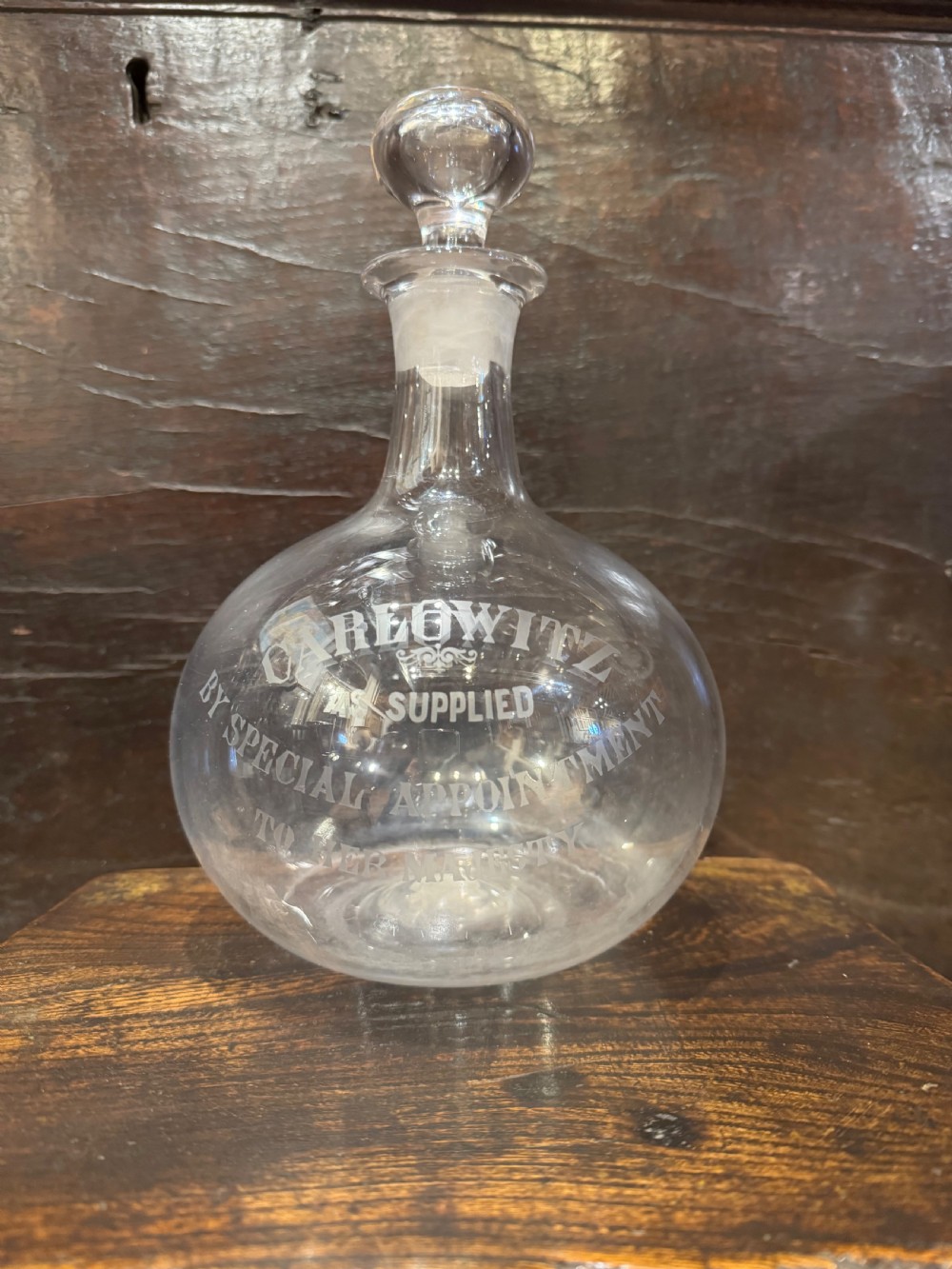 A clear bulbous glass wine flagon featuring etched lettering reading Max Greger and Co London Wine Flagon with a matching glass stopper. View III