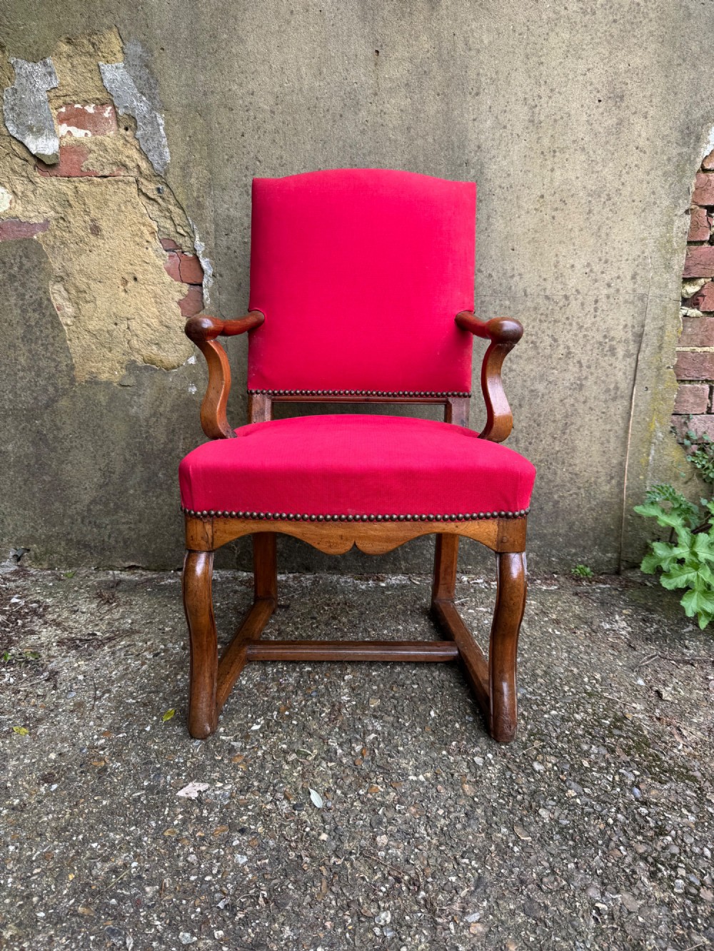 An antique French wooden armchair featuring red fabric upholstery, scrolled arms, brass stud trimming, and a rectangular stretcher base. View IV
