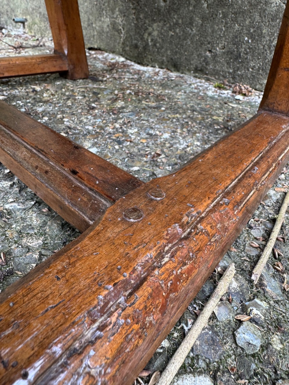An antique French wooden armchair featuring red fabric upholstery, scrolled arms, brass stud trimming, and a rectangular stretcher base. View VII