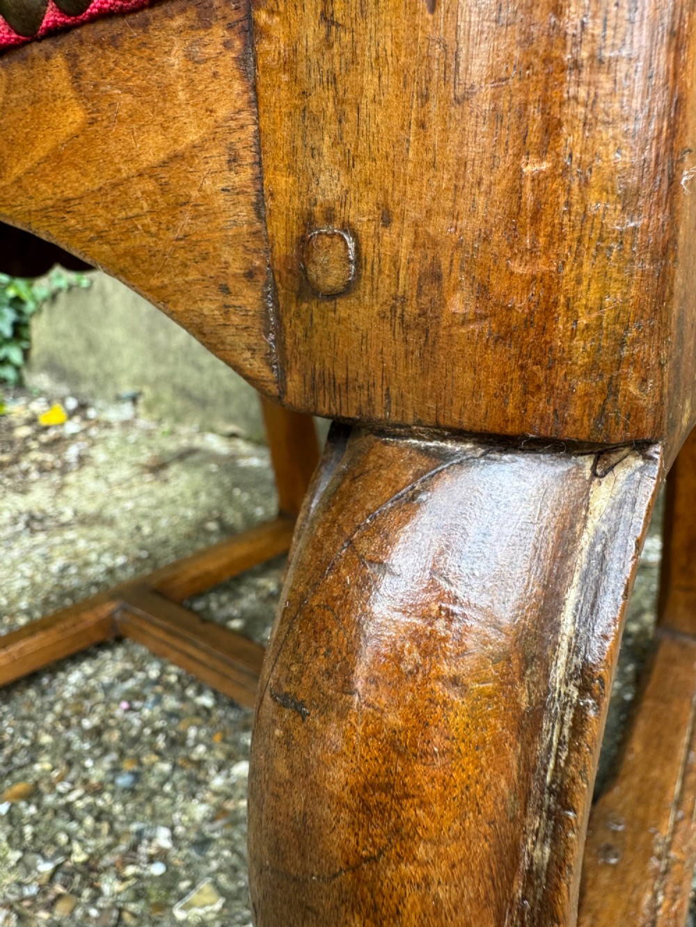 An antique French wooden armchair featuring red fabric upholstery, scrolled arms, brass stud trimming, and a rectangular stretcher base. View VIII
