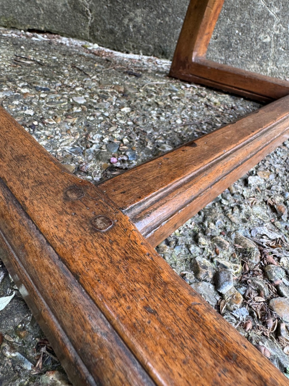 An antique French wooden armchair featuring red fabric upholstery, scrolled arms, brass stud trimming, and a rectangular stretcher base. View XI